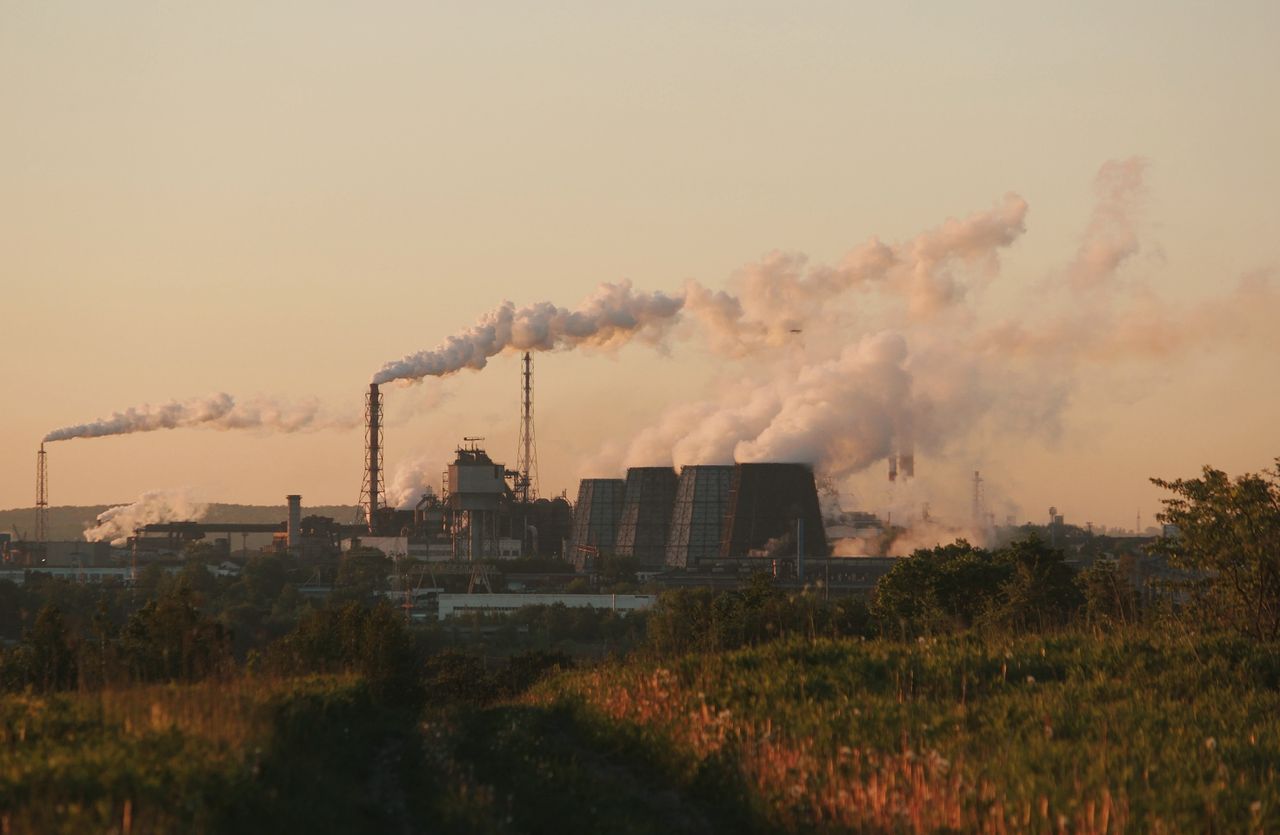 social-feed-img-03 Factory chimneys releasing smoke into the sky at sunset, highlighting industrial pollution.