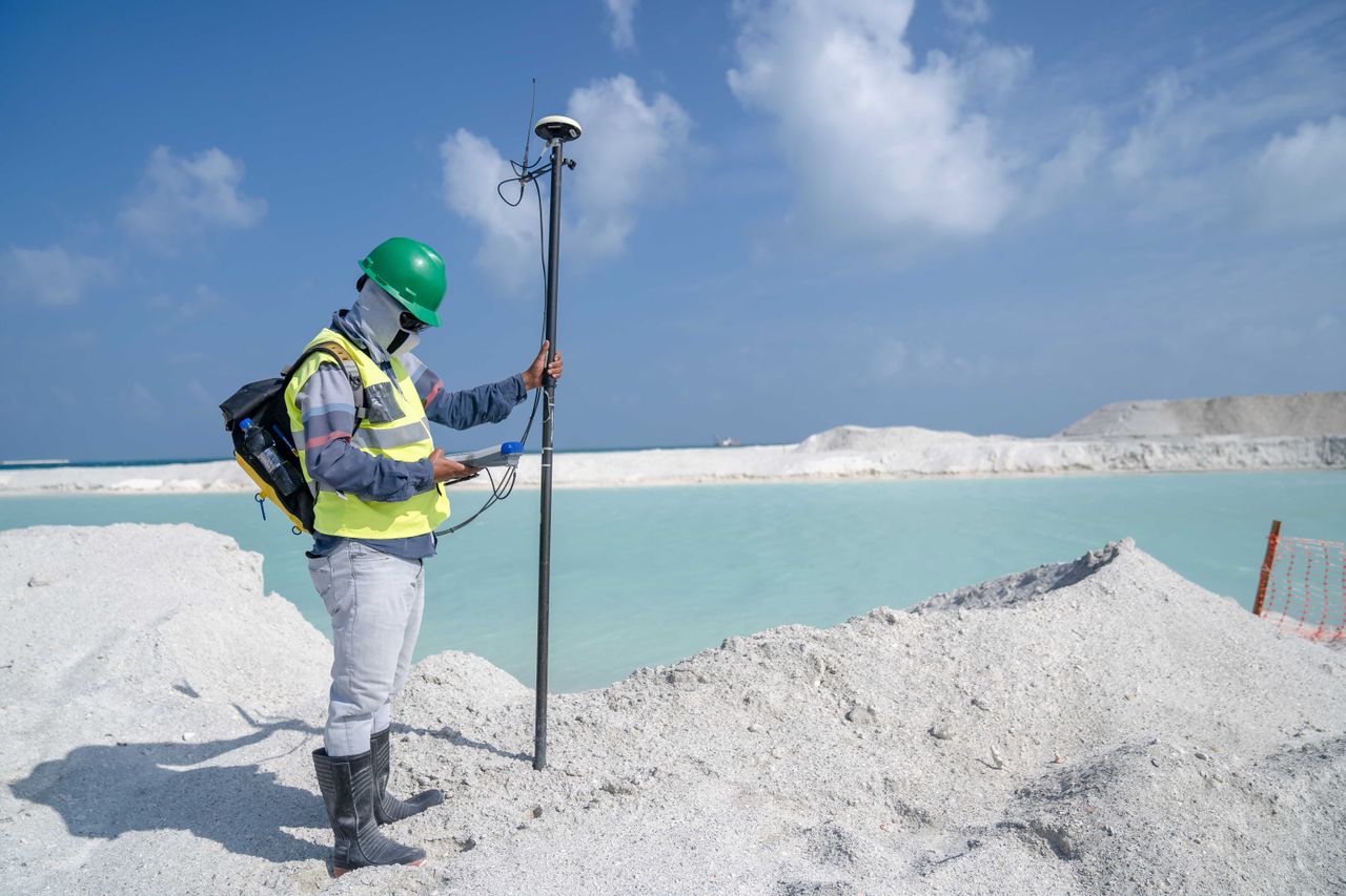 about-me-01 Surveyor in protective gear conducting measurements by a remote beach with GPS equipment.
