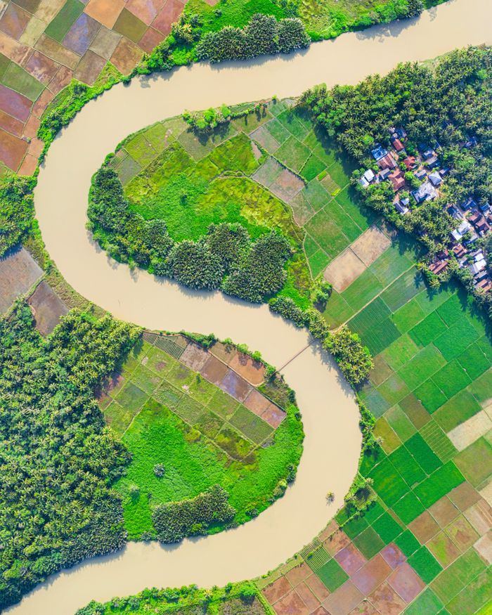 birthday-party-04 Aerial view of lush riverside farmlands in Labuhan, Indonesia, showcasing winding river bends and verdant fields.