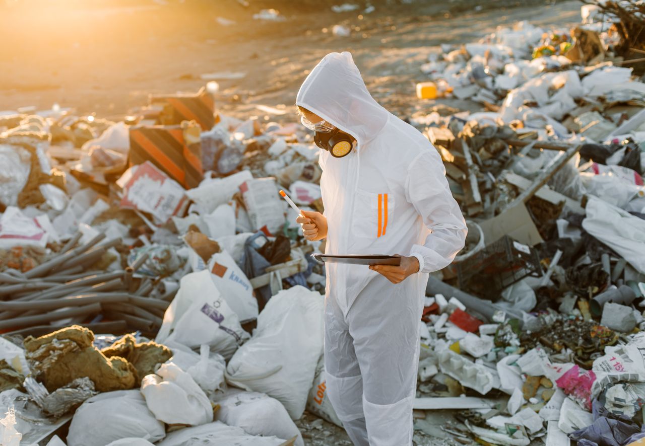 social-feed-img-01 Scientist in protective suit inspecting a landfill site at sunset.